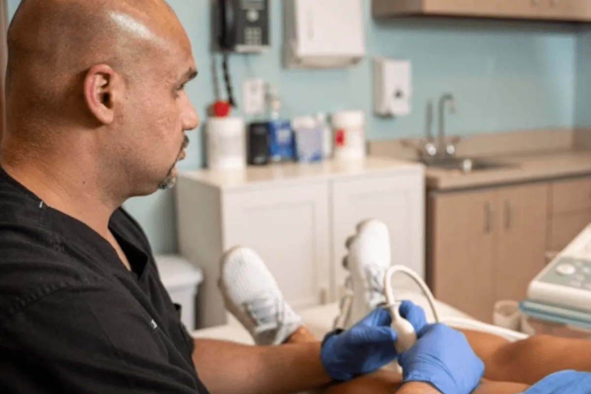 Board-certified physiatrist Dr. Ahmad examining knee arthritis patient using diagnostic ultrasound imaging equipment at Stem Cell Carolina Charlotte office