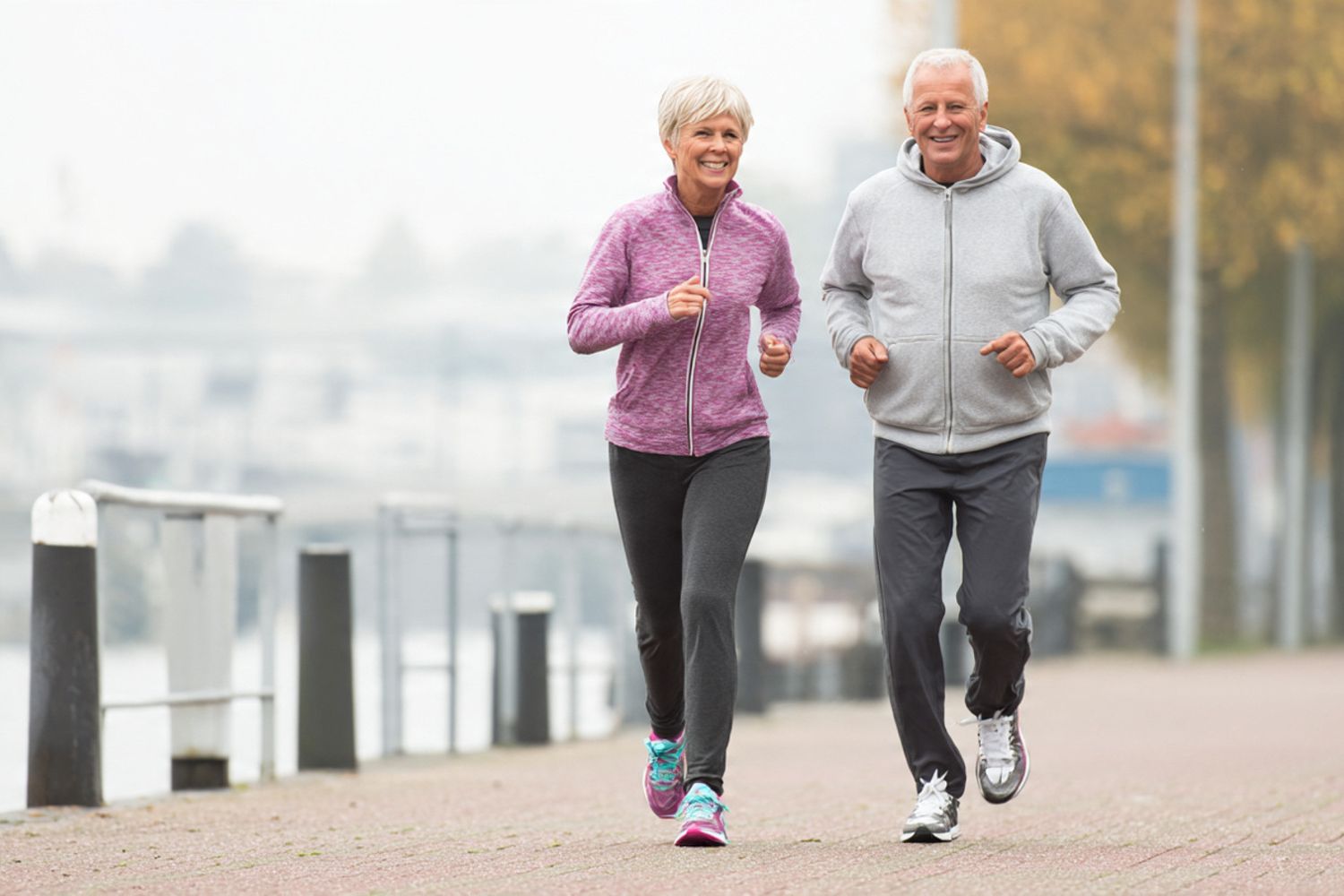 Active couple jogging together outdoors near a waterfront on a clear morning